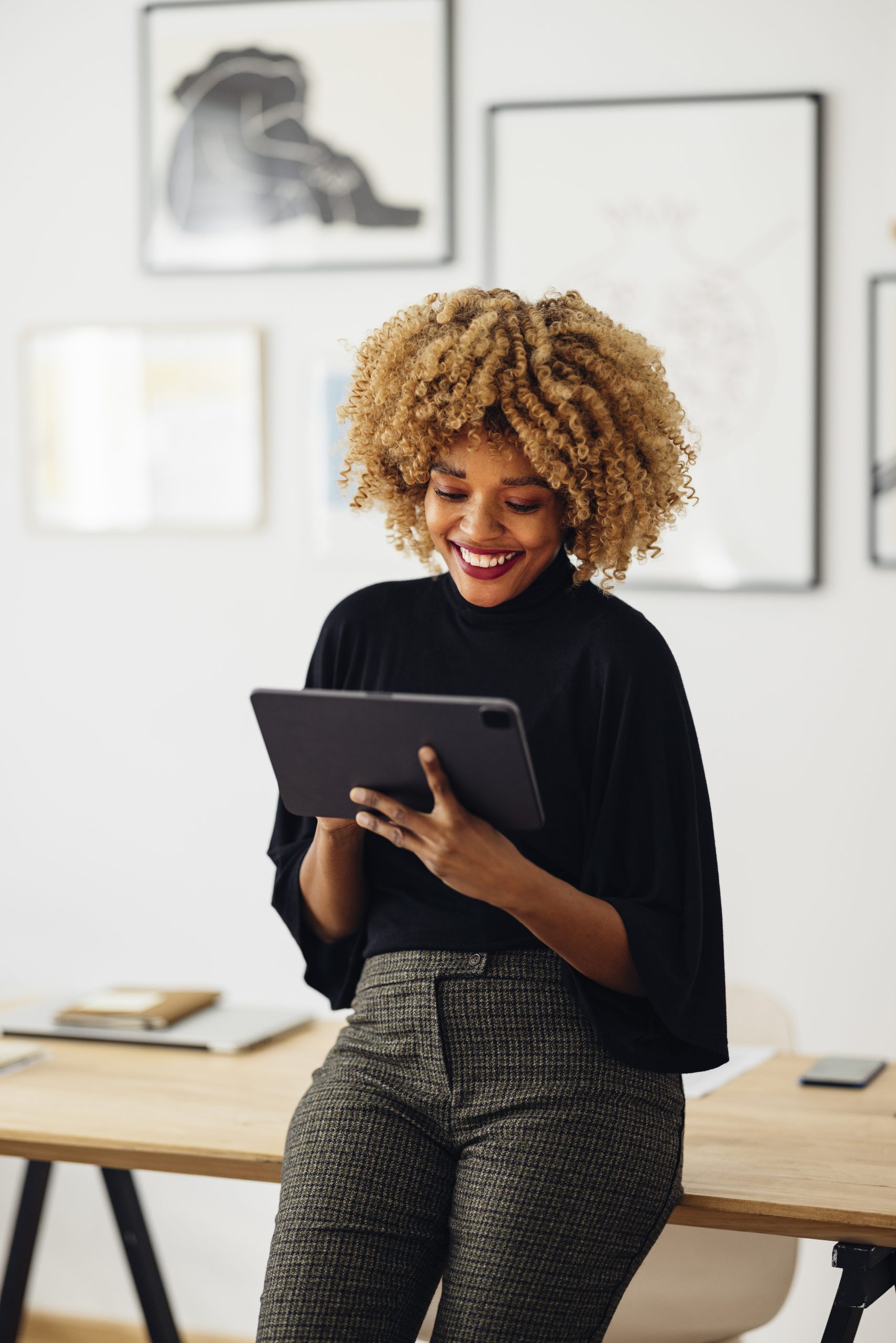 Happy Businesswoman Sitting on Her Desk Using Her Tablet